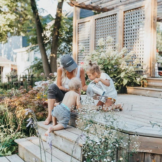 @birdofbalance A mom on her backyard deck watching one of her kids fill a glass of water with her white Santevia MINA Alkaline Pitcher
