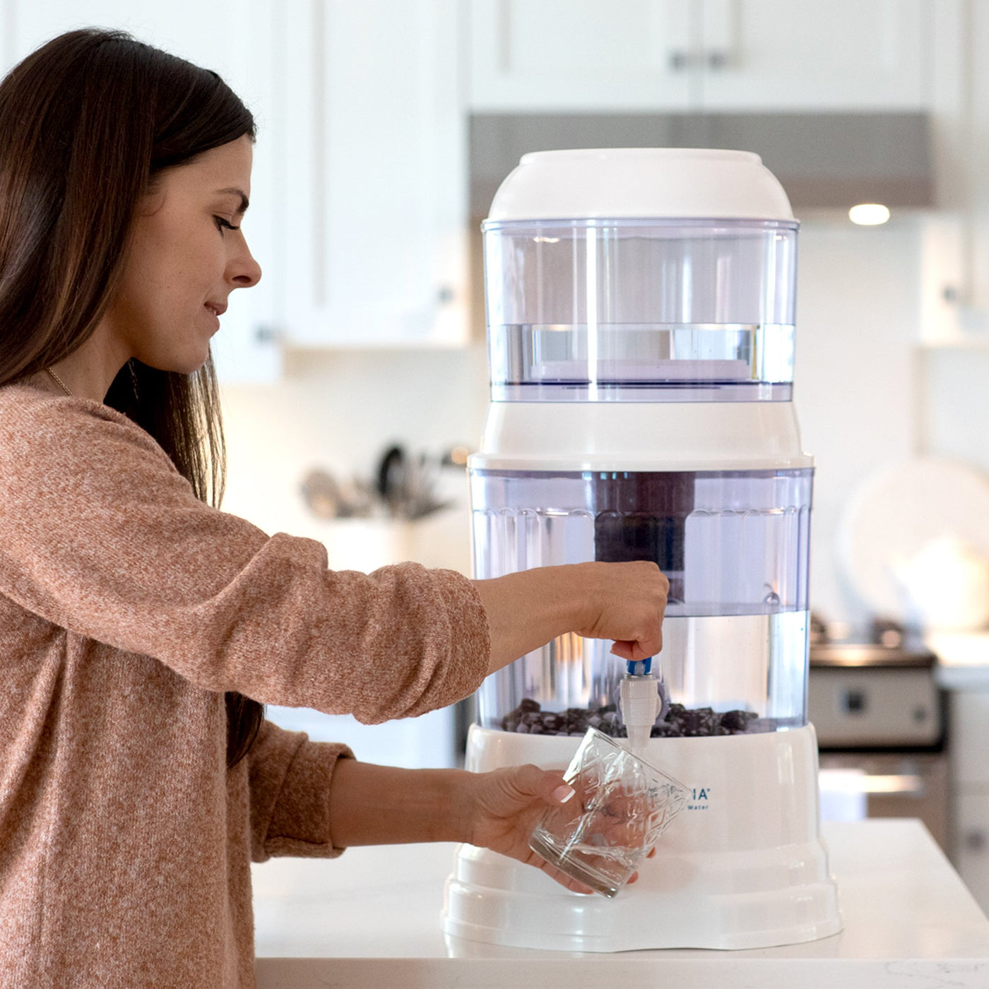  A woman filling a glass from her Santevia Gravity Water System